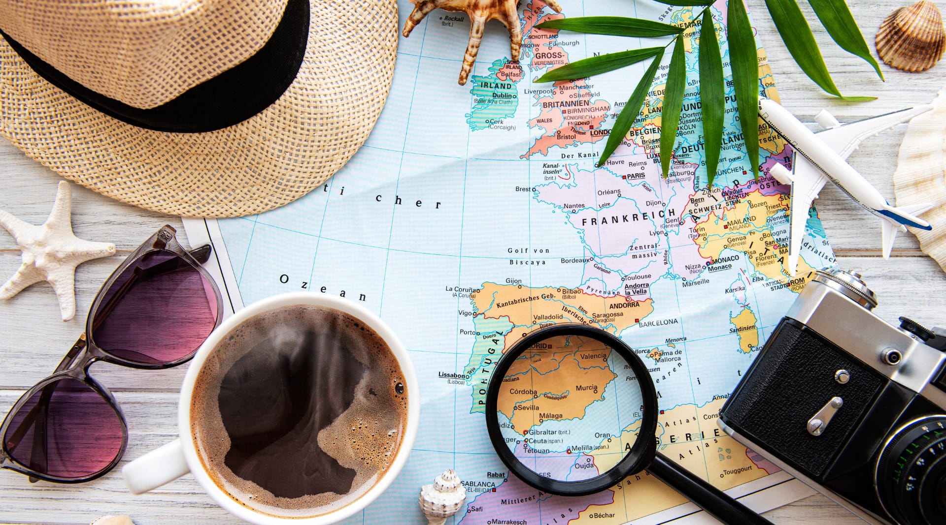 Flat lay of eco-friendly travel essentials including a hat, coffee, camera, and map of Europe — symbolizing sustainable travel tips for mindful explorers.